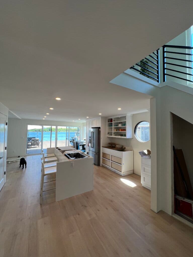 Modern kitchen interior with open layout, large windows overlooking water, and sleek design.