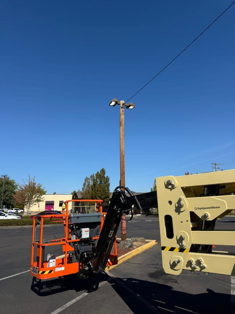 Aerial lift equipment positioned next to a utility pole under a clear blue sky.