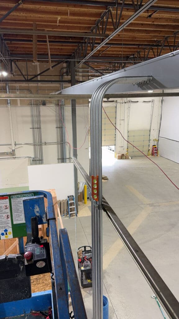 View from a lift showing overhead metal framing and an empty warehouse space.