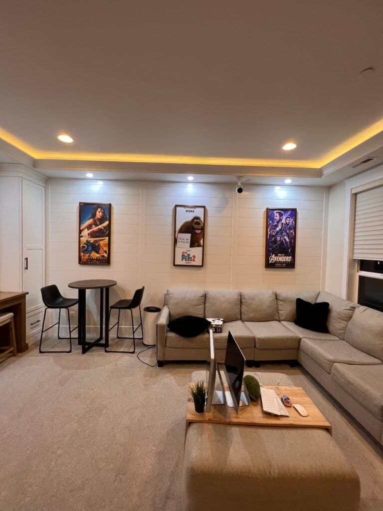 Modern living room with sectional sofa, bar stools, artwork, and cozy lighting.
