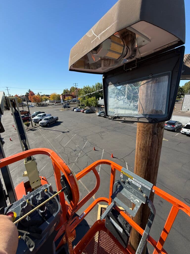 View from a cherry picker overlooking a parking lot with vehicles and power lines.