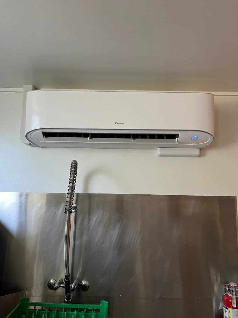 Wall-mounted air conditioner in a commercial kitchen setting.