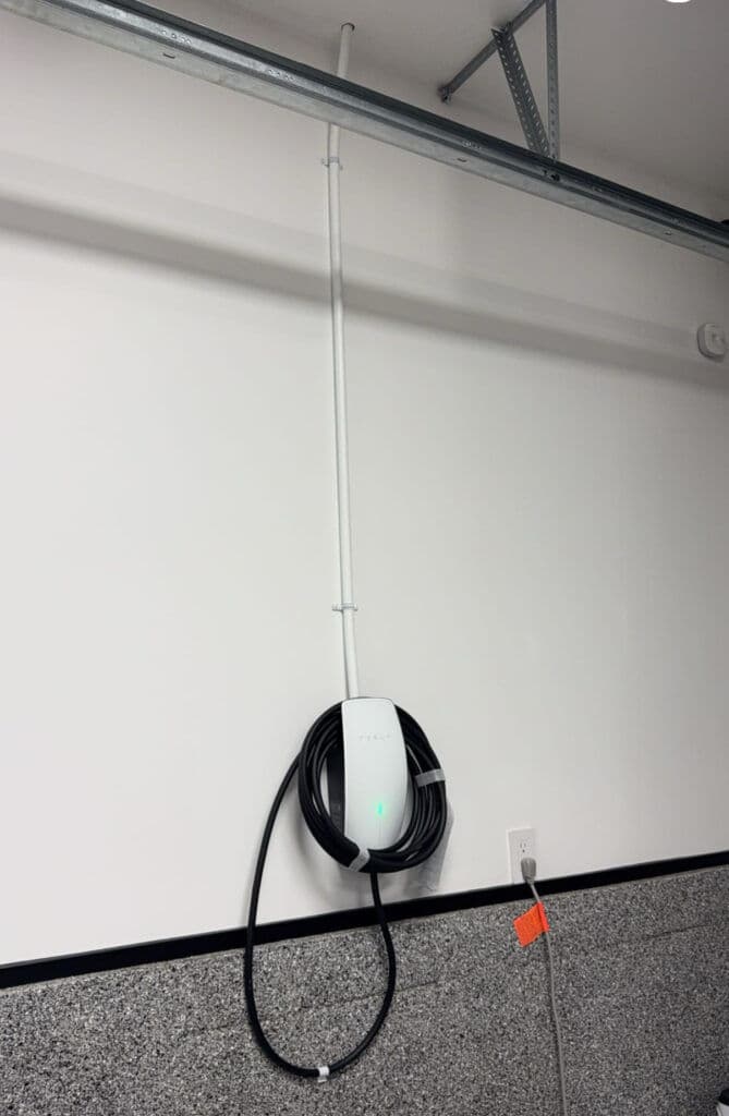 Wall-mounted EV charger with coiled cable for electric vehicle charging station.