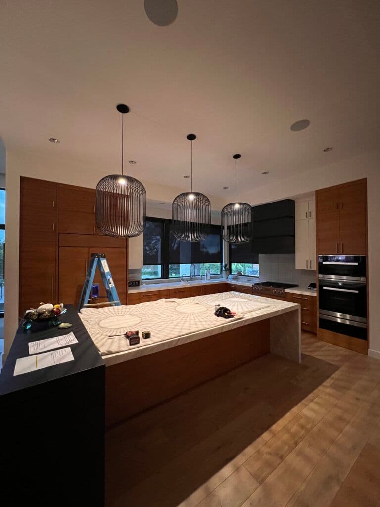 Modern kitchen with pendant lights, wooden cabinetry, and a large central island.