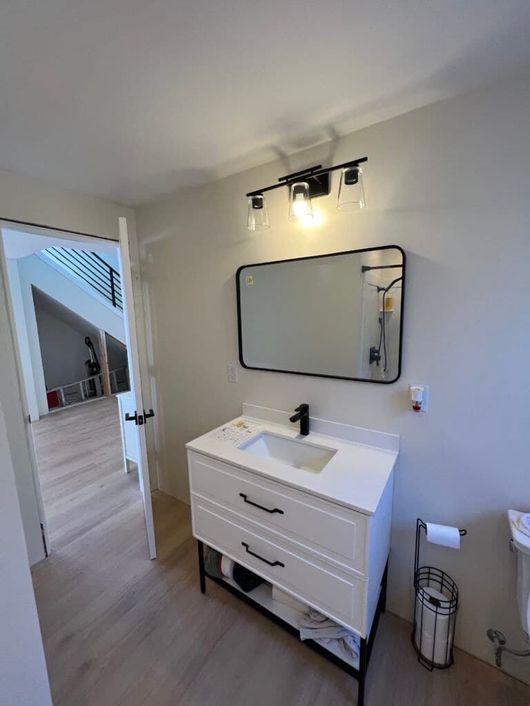 Modern bathroom vanity with white sink, mirror, and stylish lighting in a bright, minimalist space.